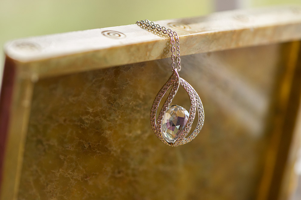 Crystal drop pendant necklace arranged on a stone ledge
