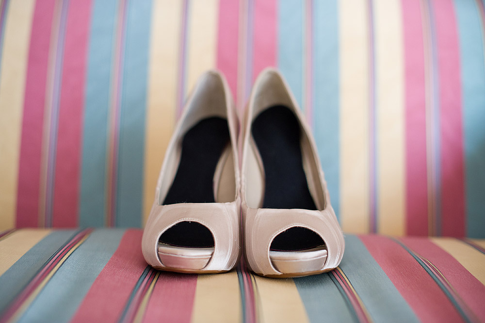 Blush peep-toe bridal shoes on a striped chair