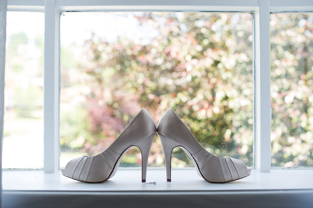 Gray peep-toe bridal shoes on a window ledge