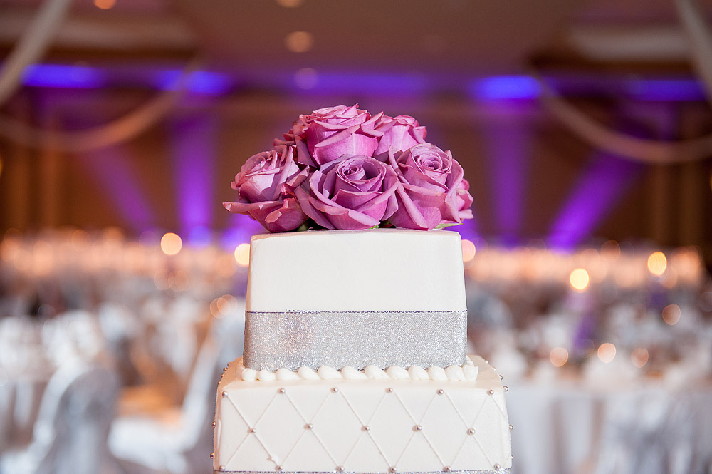 White-and-silver wedding cake topped with pink roses