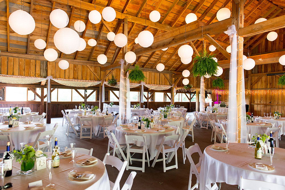 Rustic barn reception with white tables and hanging lanterns