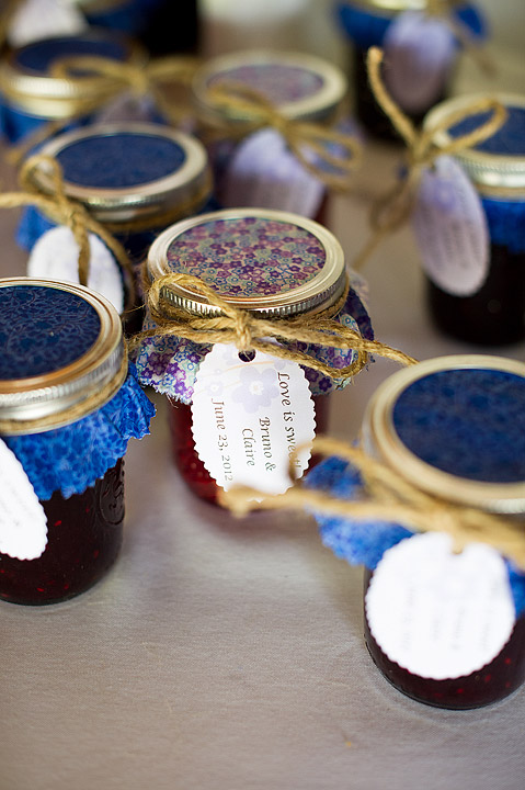 Small jars of colorful wedding favors with a handwritten tag