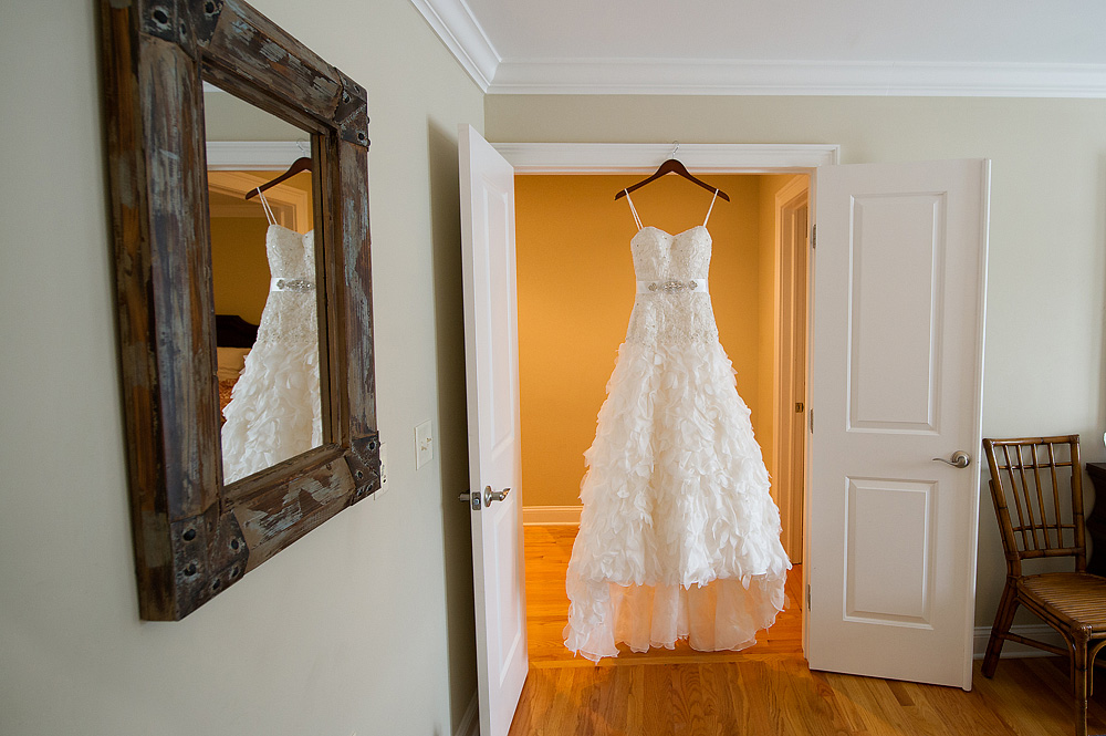 Lace wedding dress hanging in a bright doorway