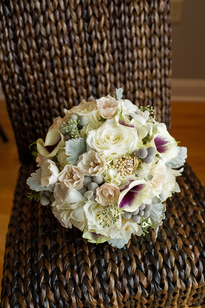 Ivory-and-purple bridal bouquet resting on a woven chair