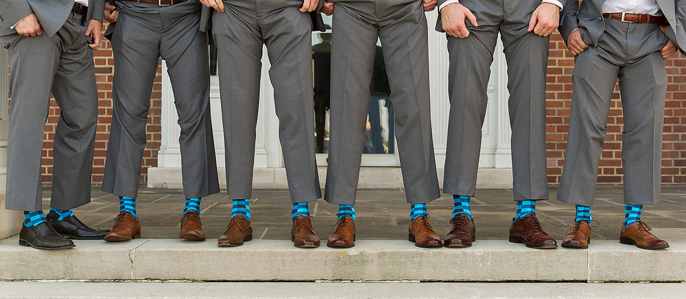 Groomsmen showing colorful socks beneath gray suits