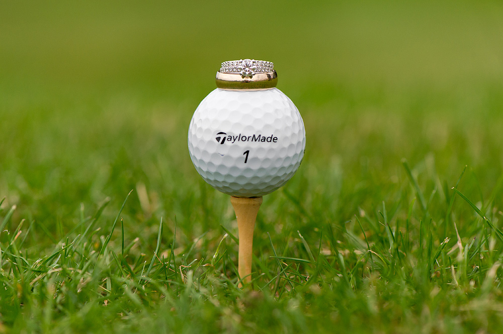 Wedding rings balanced on a golf ball and tee