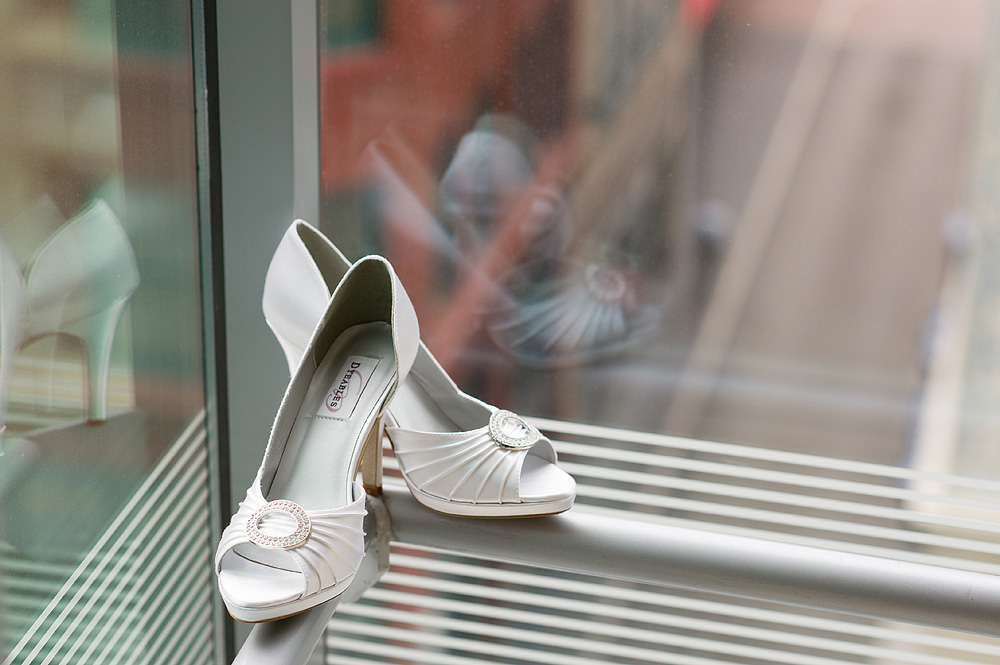 White peep-toe bridal shoes on a window ledge