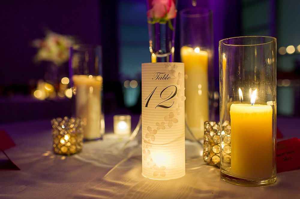 Candlelit table number twelve at a purple-lit reception