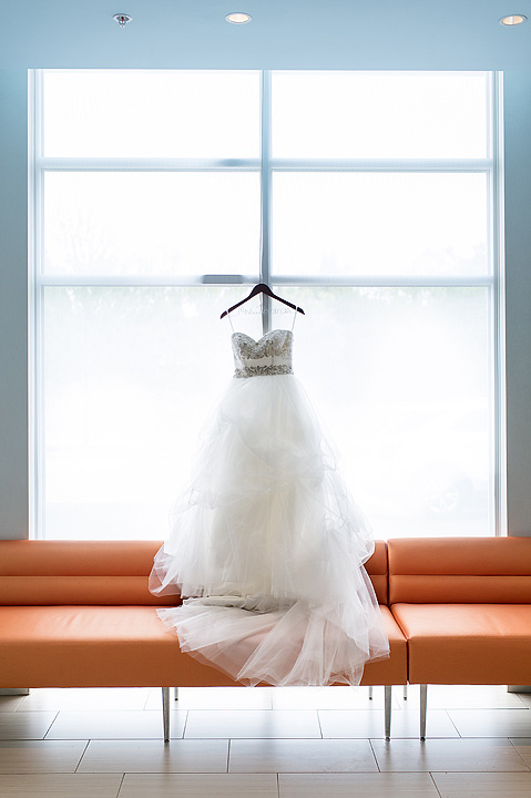 White wedding dress hanging before a large bright window