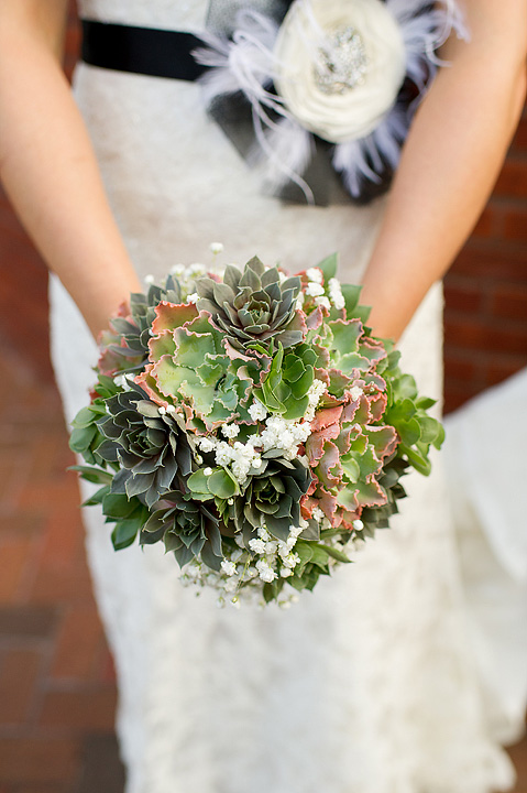 Succulent bridal bouquet held against a white wedding dress