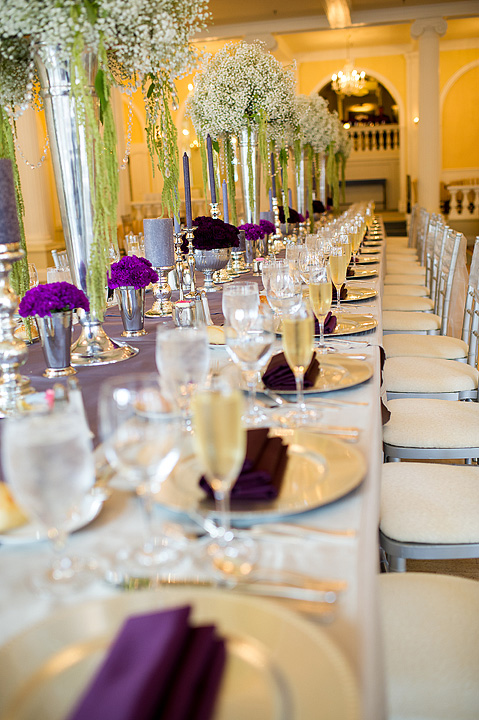 Reception table with purple napkins and tall floral arrangements