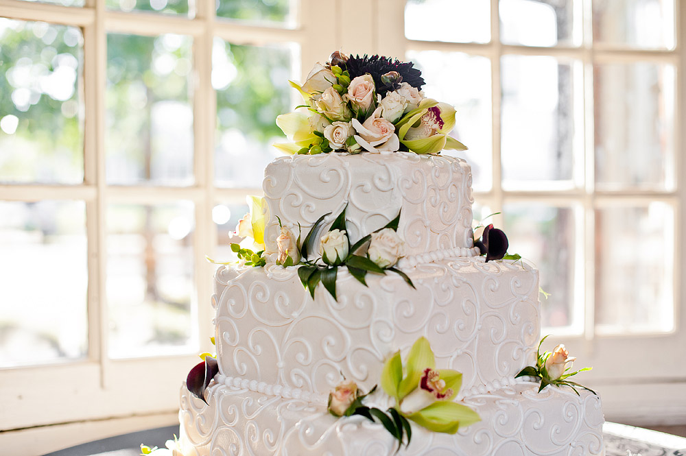 White tiered wedding cake decorated with flowers and fruit