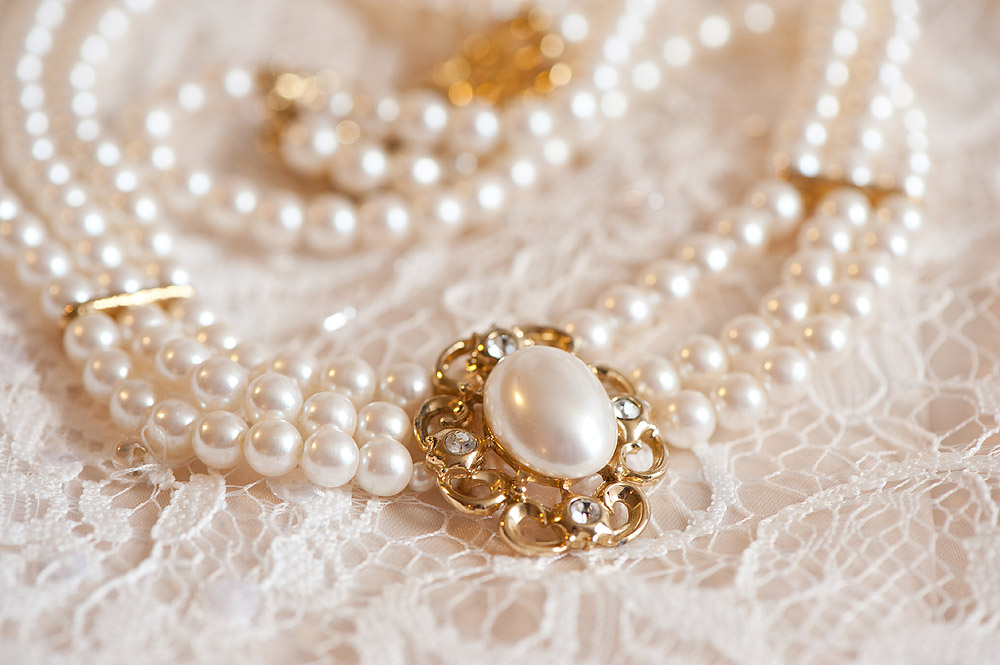 Pearl necklace and earrings arranged on lace