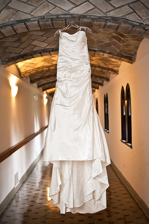 Strapless white wedding dress hanging in a stone hallway