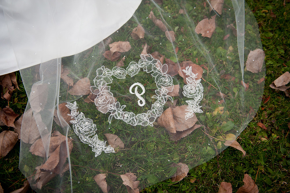 Monogrammed wedding veil spread over fallen leaves