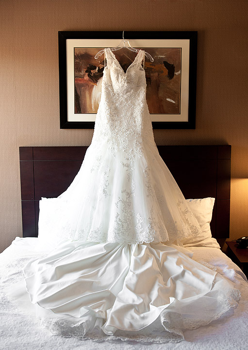 Lace wedding dress displayed over a dark sofa
