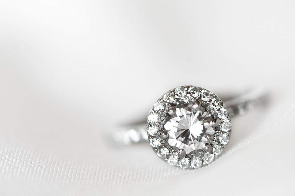 Round halo diamond engagement ring on white fabric