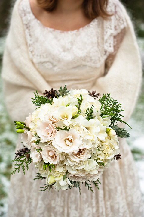 Ivory bridal bouquet held against a lace wedding dress