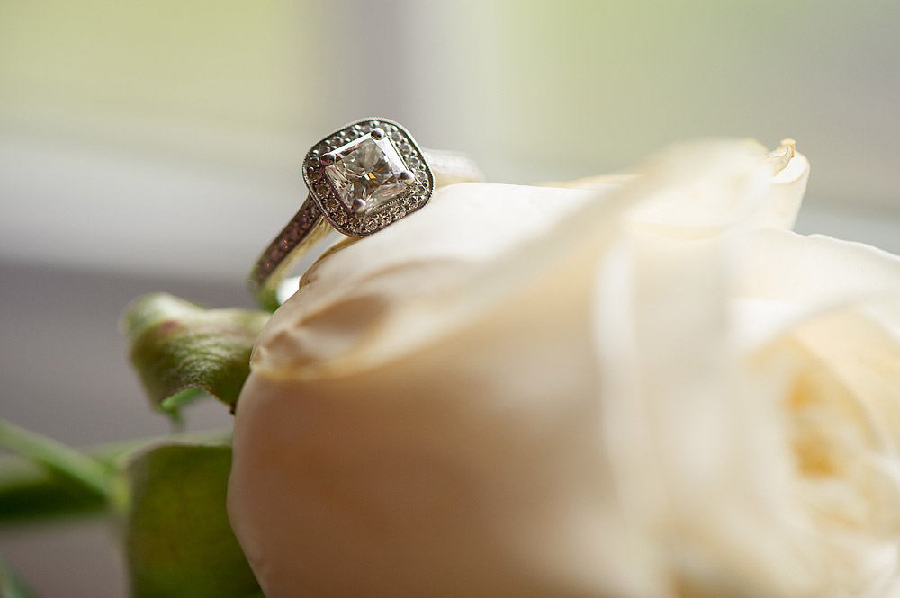 Diamond engagement ring resting on a white rose