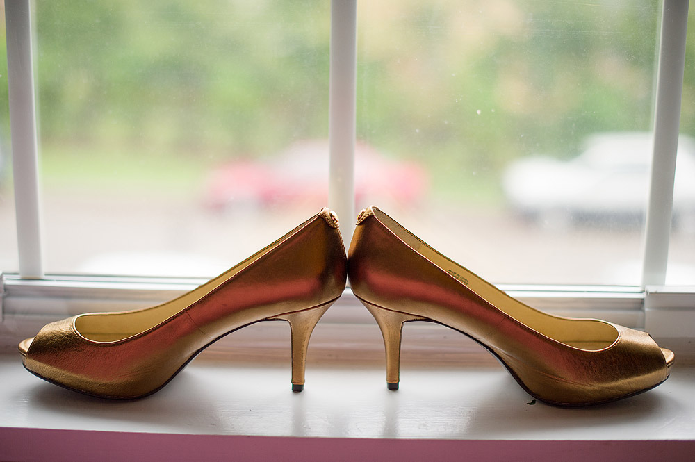 Gold bridal shoes arranged heel-to-heel on a window ledge