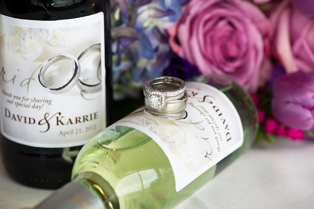 Wedding rings displayed with wine bottles and purple flowers