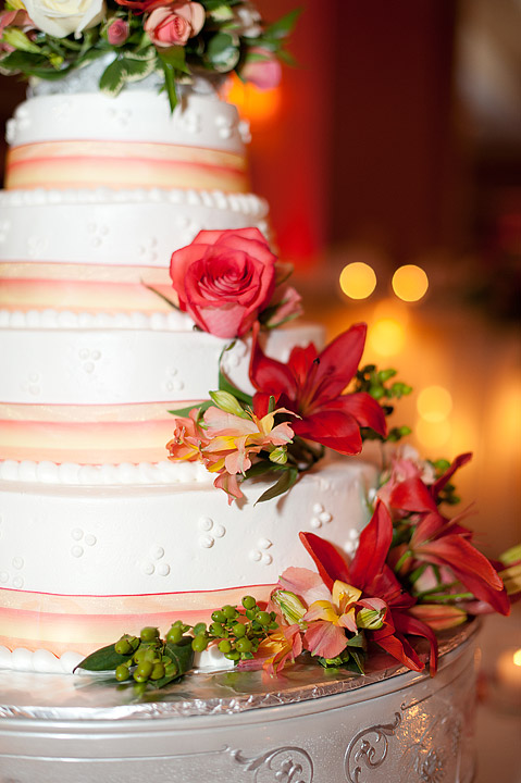 White wedding cake decorated with coral roses and flowers