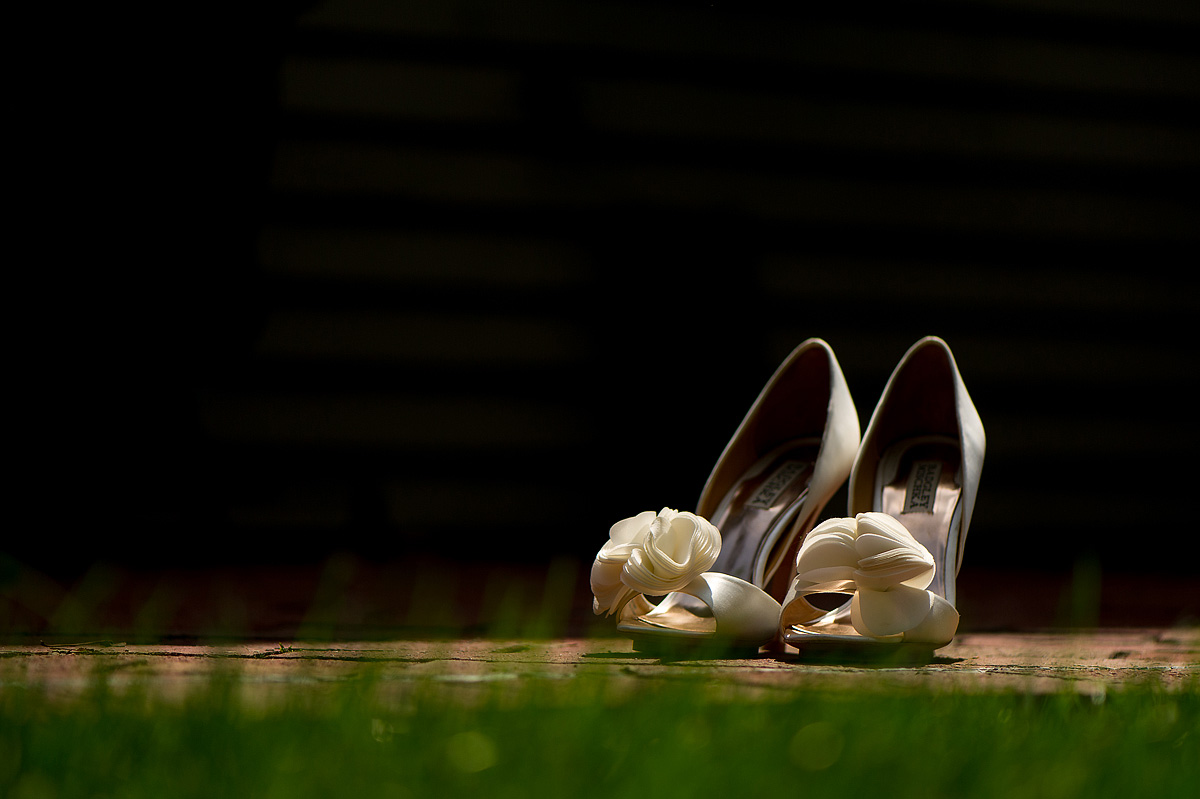 Ivory bridal shoes with fabric flowers on a brick ledge