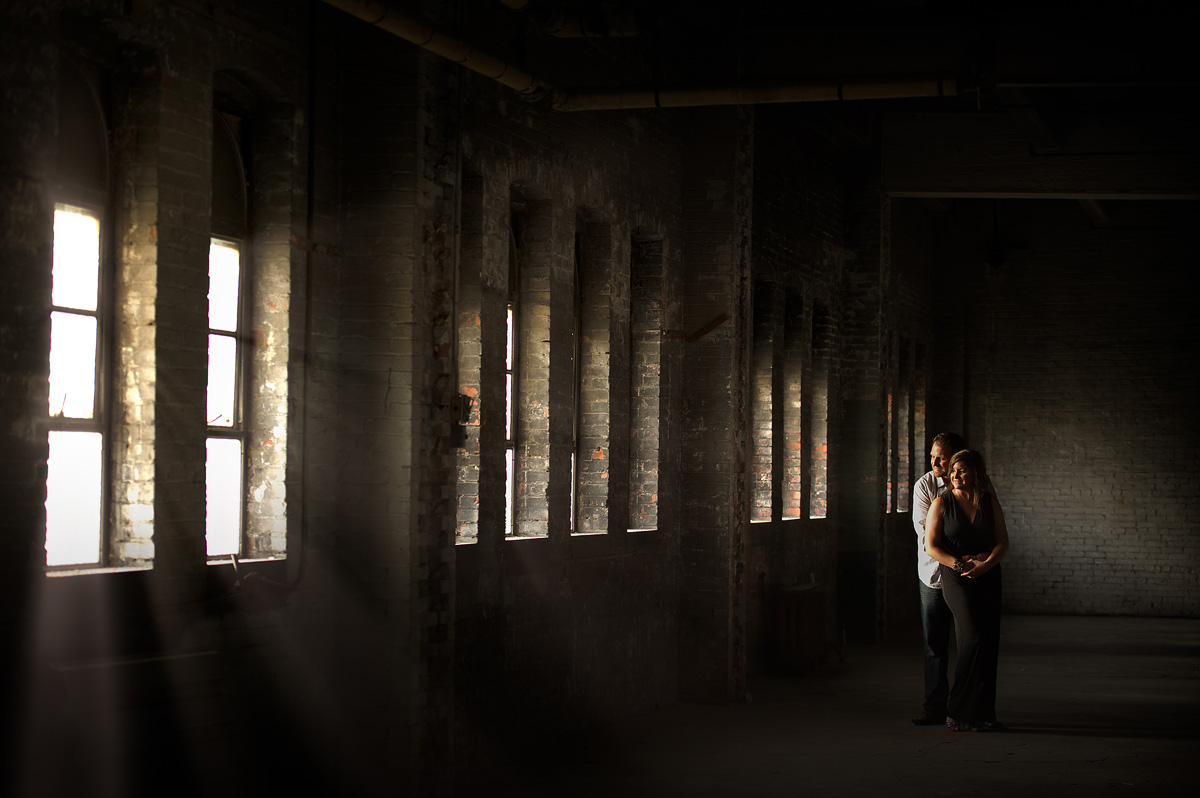 Couple standing inside a shadowy industrial building