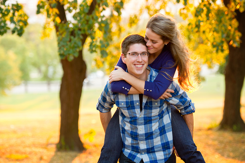 Playful piggyback pose beneath yellow autumn trees