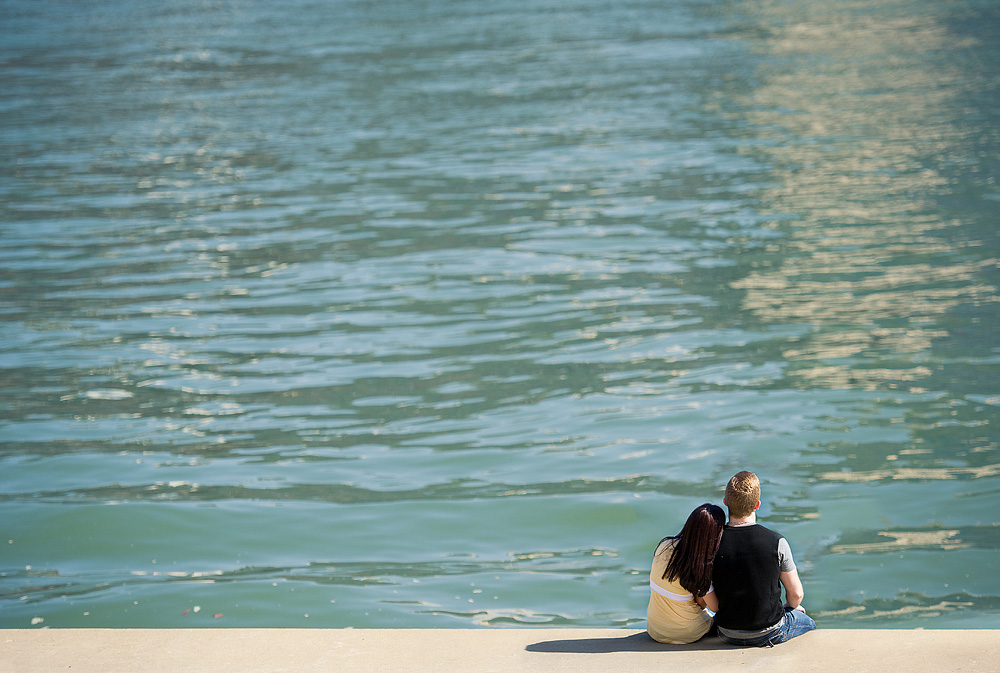 Couple seated together at the edge of blue water