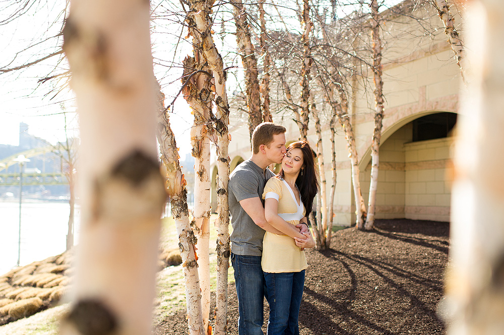 Couple standing among white-barked trees beside a river