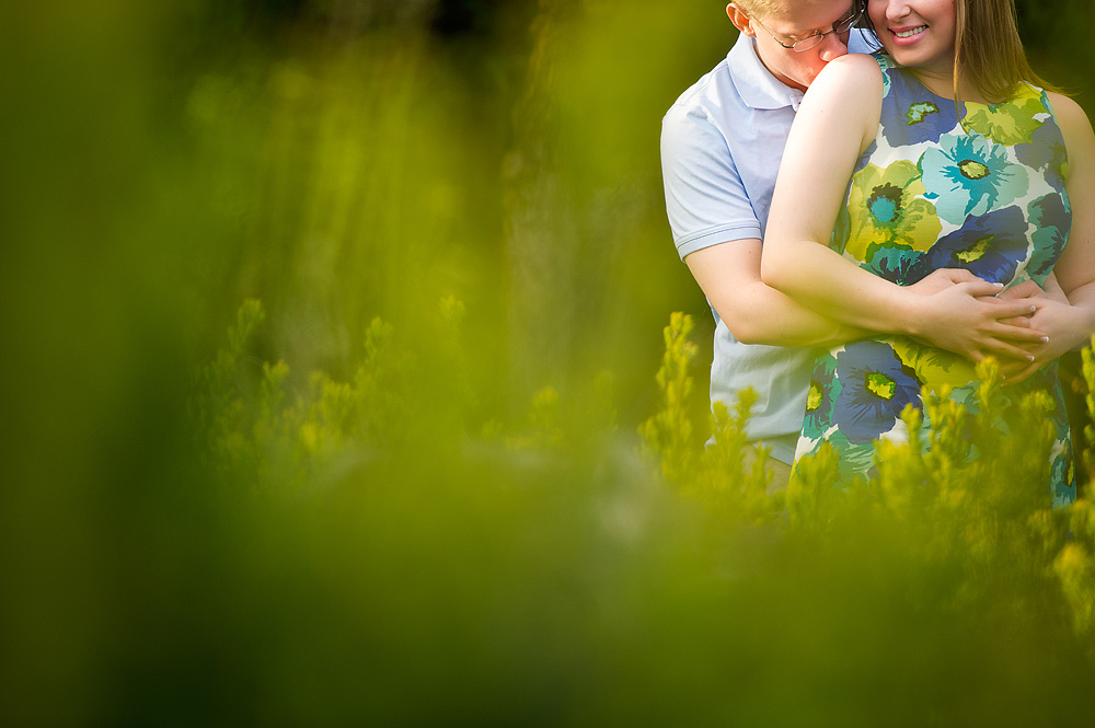 Couple embracing behind soft green foliage