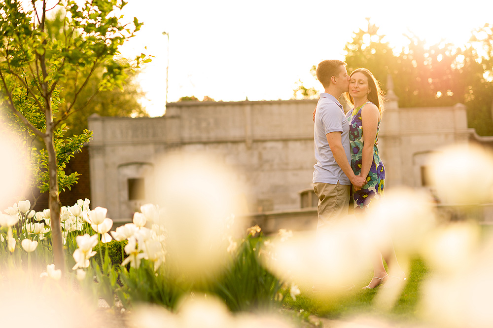 Couple kissing in warm sunset light among white flowers