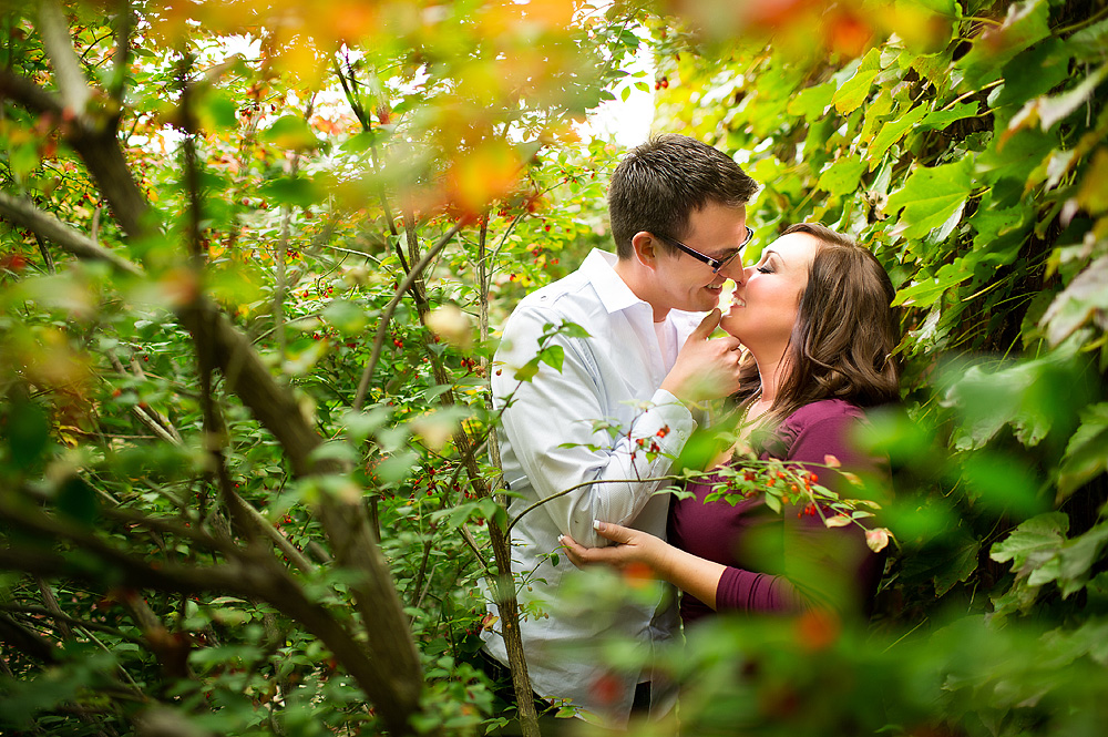 Couple kissing beneath green tree branches