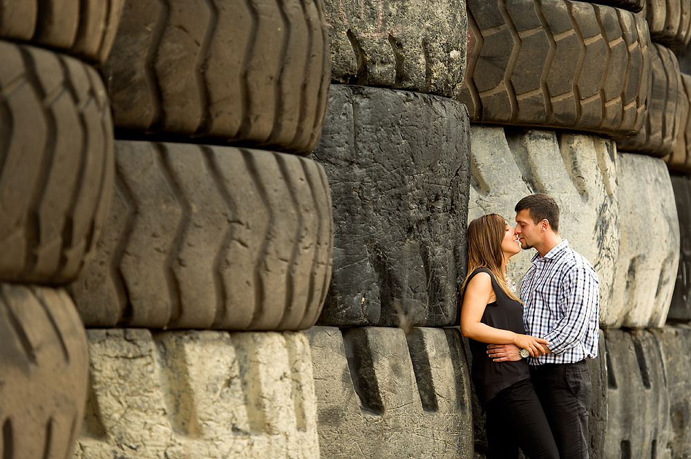 Couple embracing beside a stack of large tires in Pittsburgh's Strip District