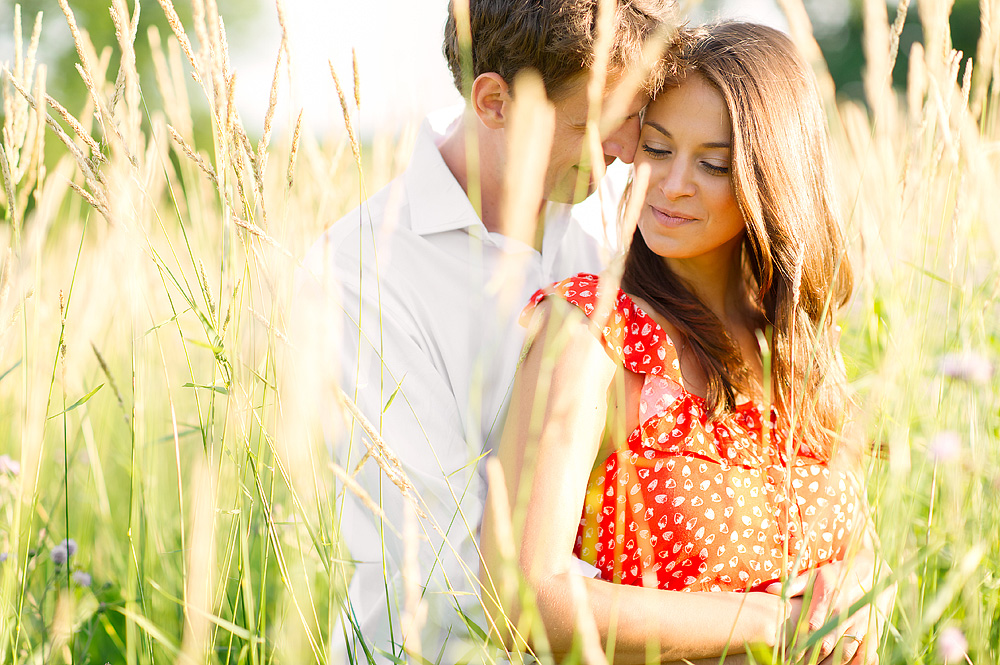 Couple standing close together in tall sunlit grass
