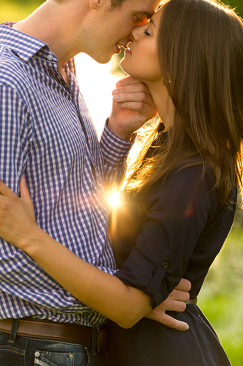 Close-up of a couple kissing in warm sun flare