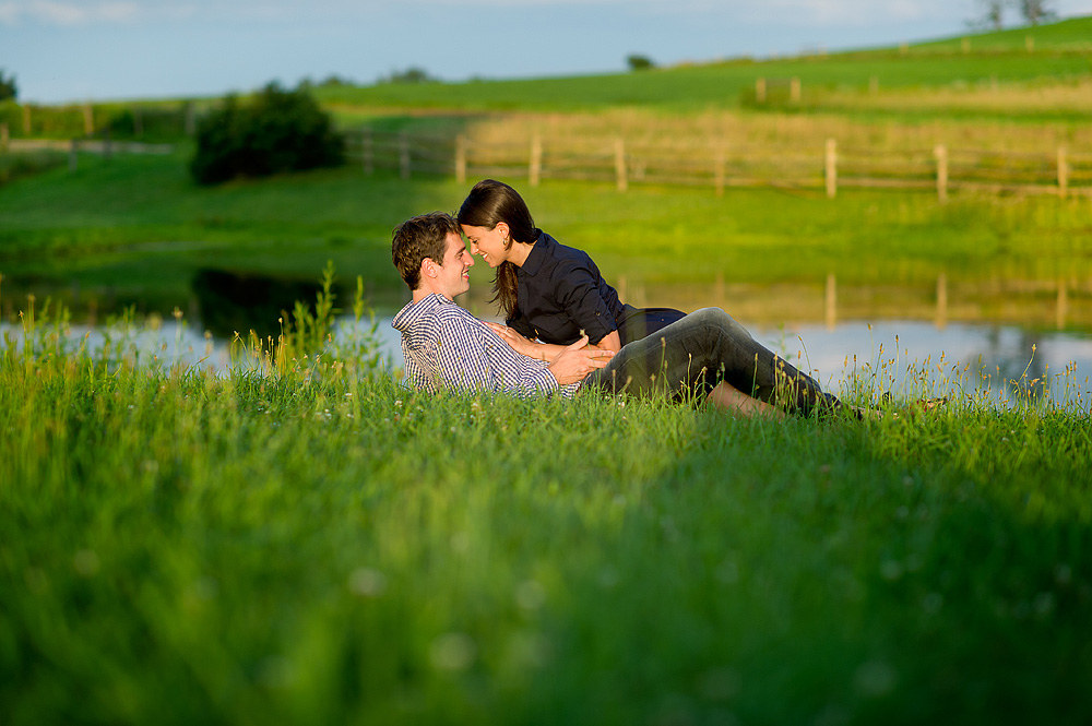 Couple lying together in the grass beside a pond