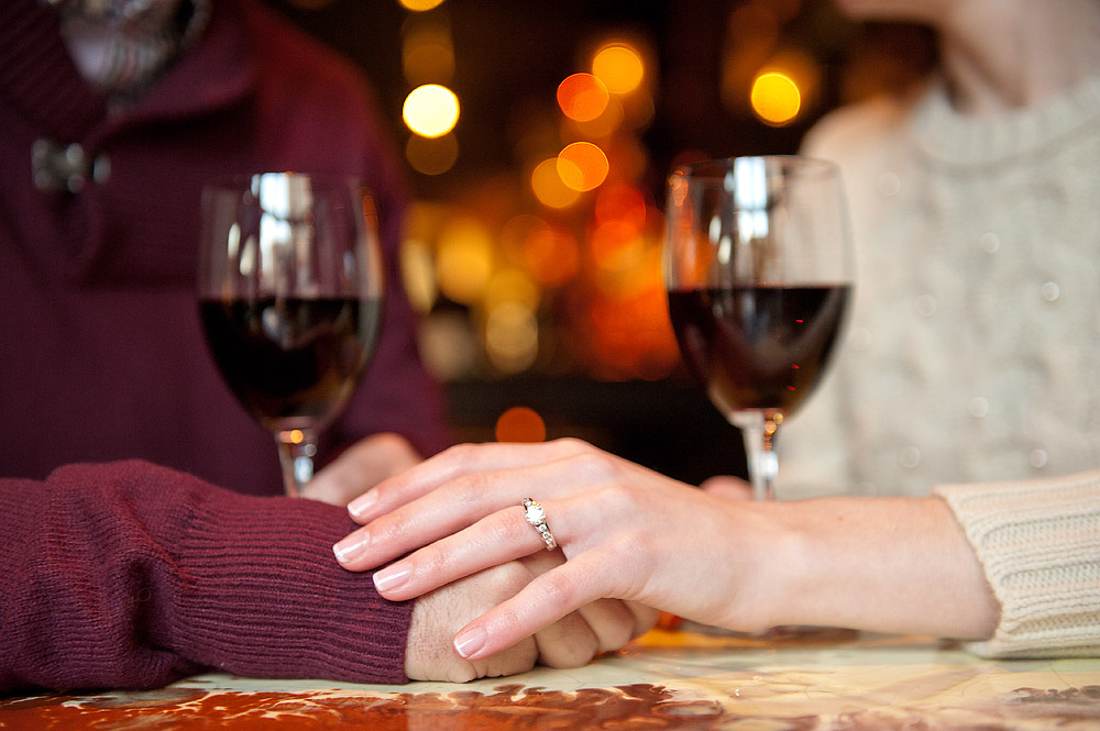 Engagement ring visible as a couple holds hands across a restaurant table
