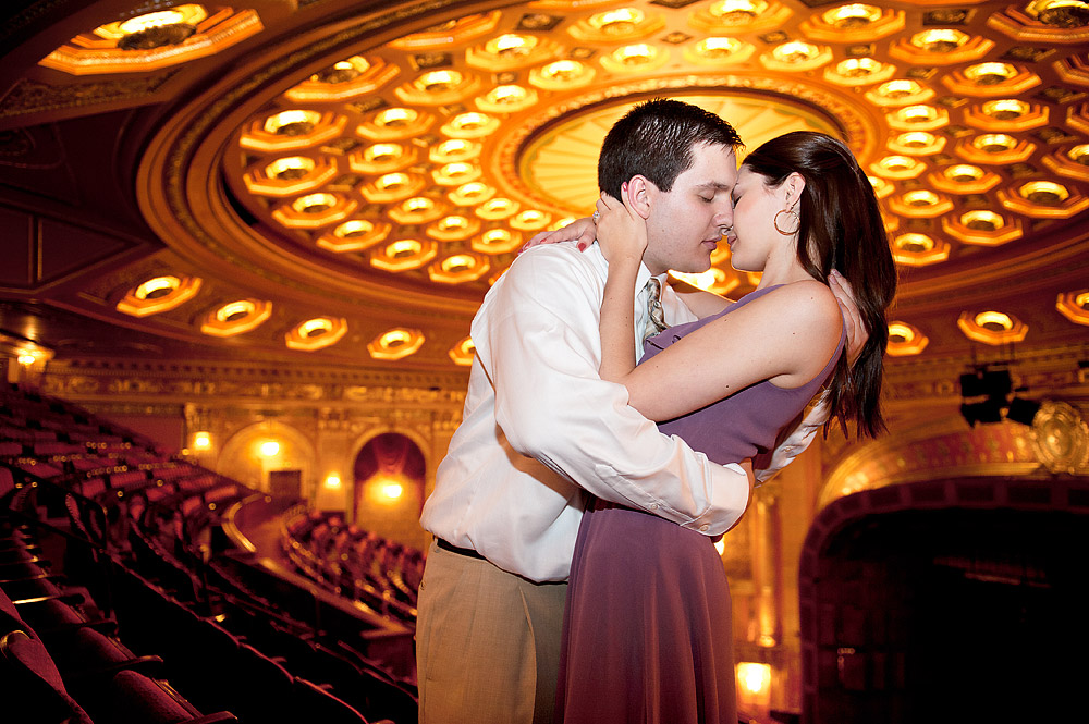 Couple embracing beneath an ornate theater ceiling