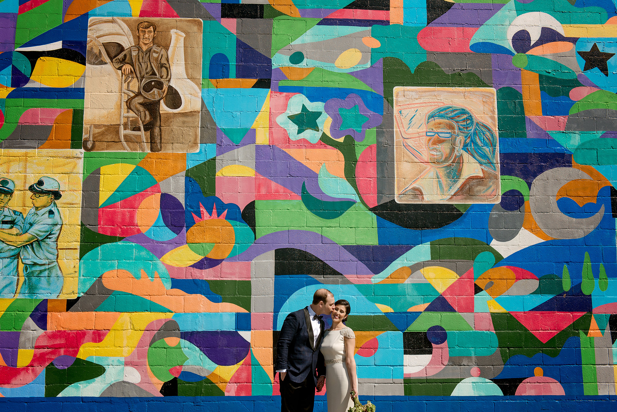 Wedding couple standing before a colorful Pittsburgh mural