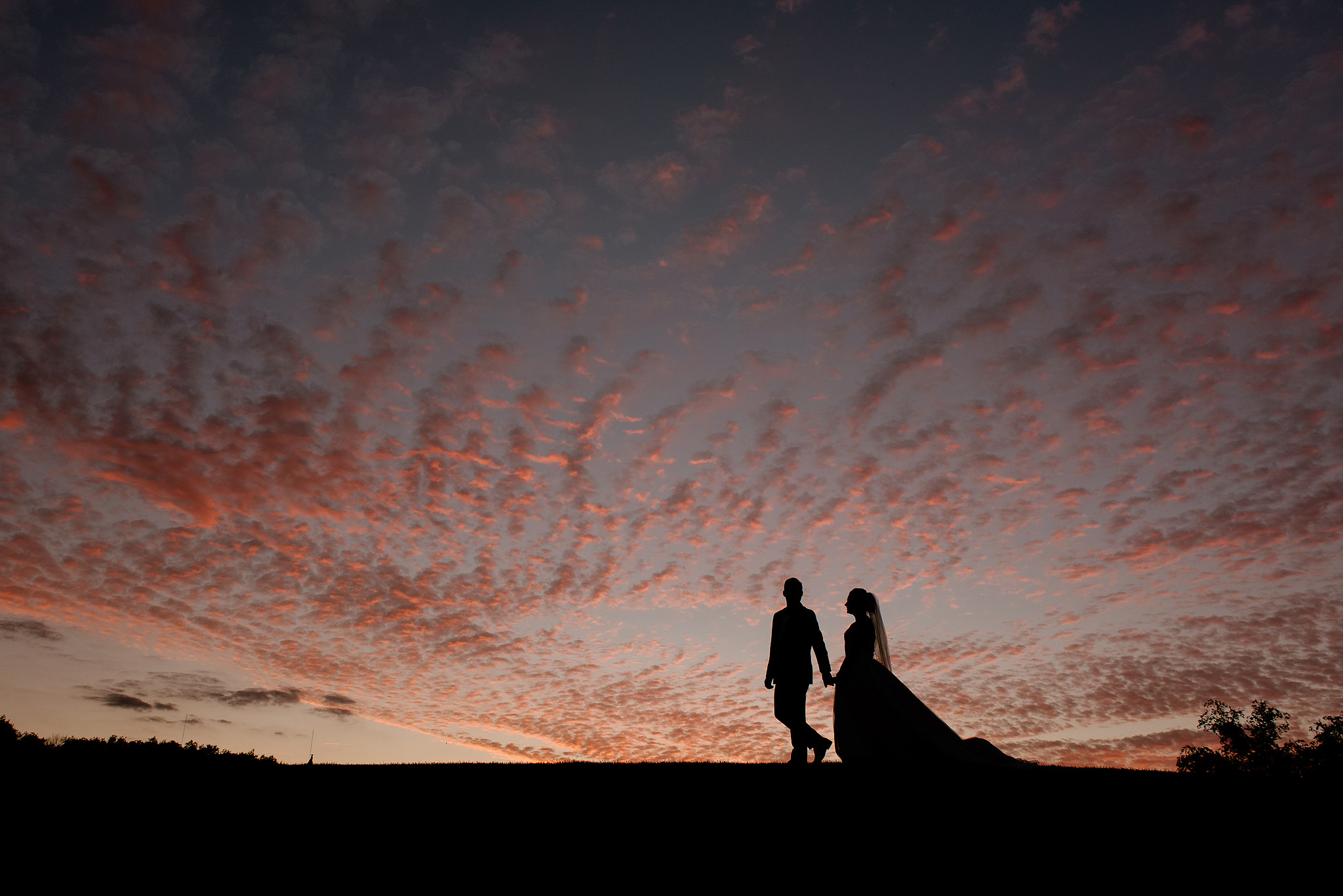 Wedding couple silhouetted against a dramatic red sunset sky