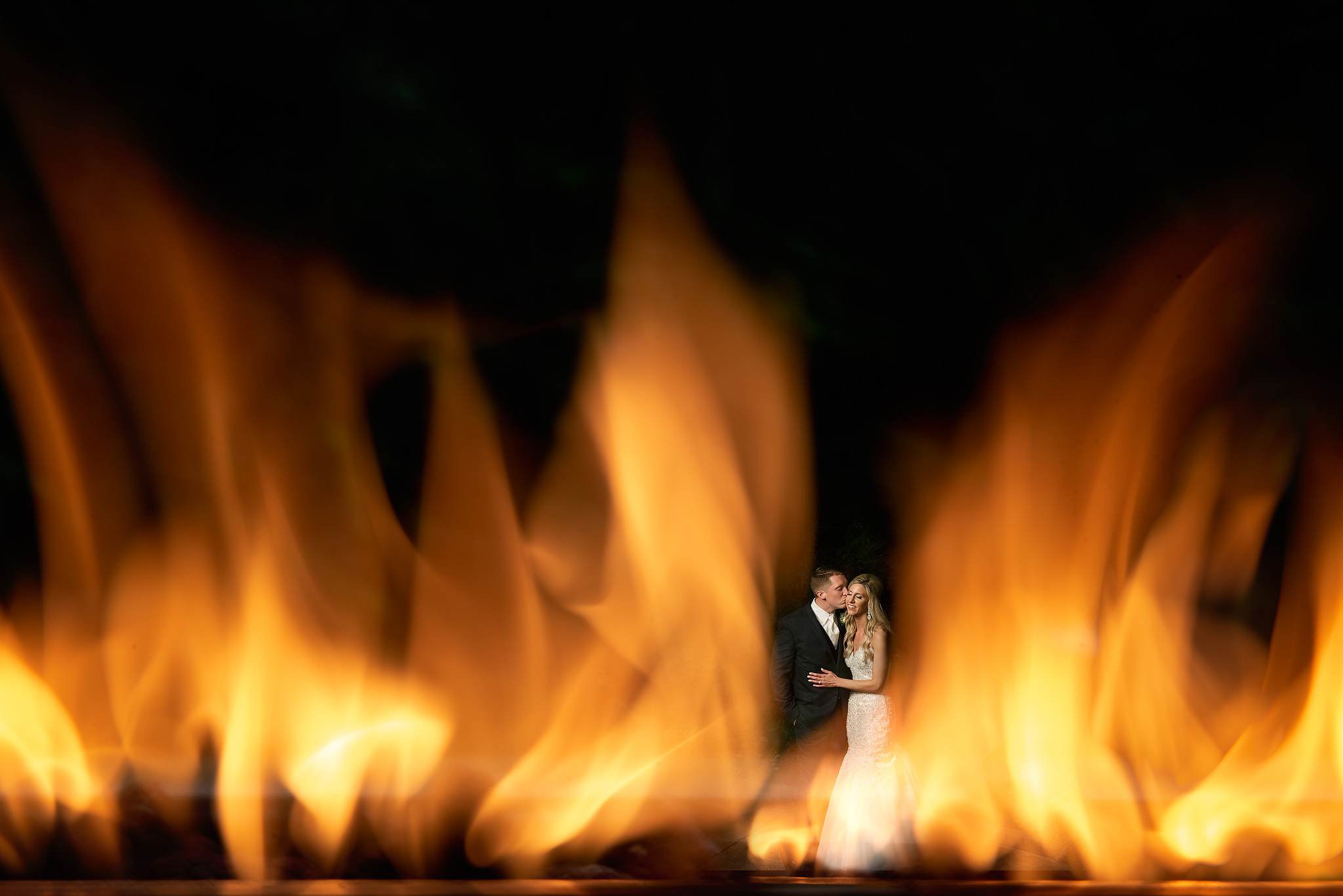 Wedding couple seen through the glow of a fireplace