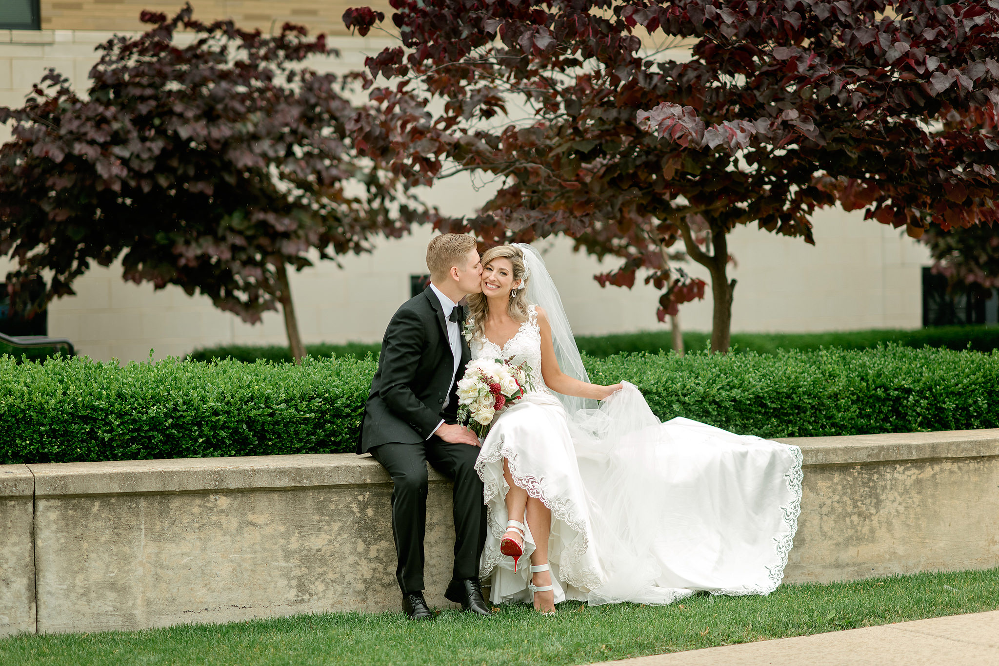 Newlyweds seated beneath a red-leaf tree