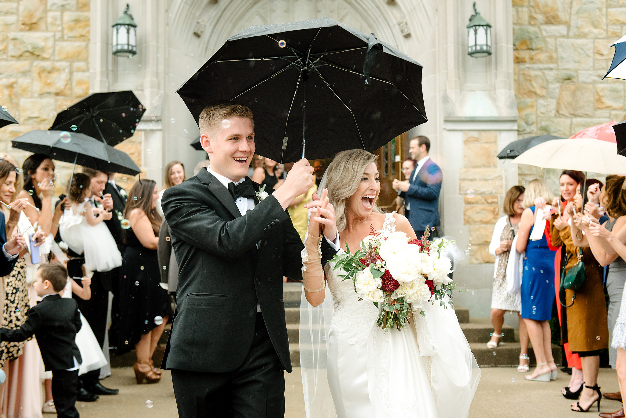 Newlyweds celebrating beneath umbrellas after their church exit