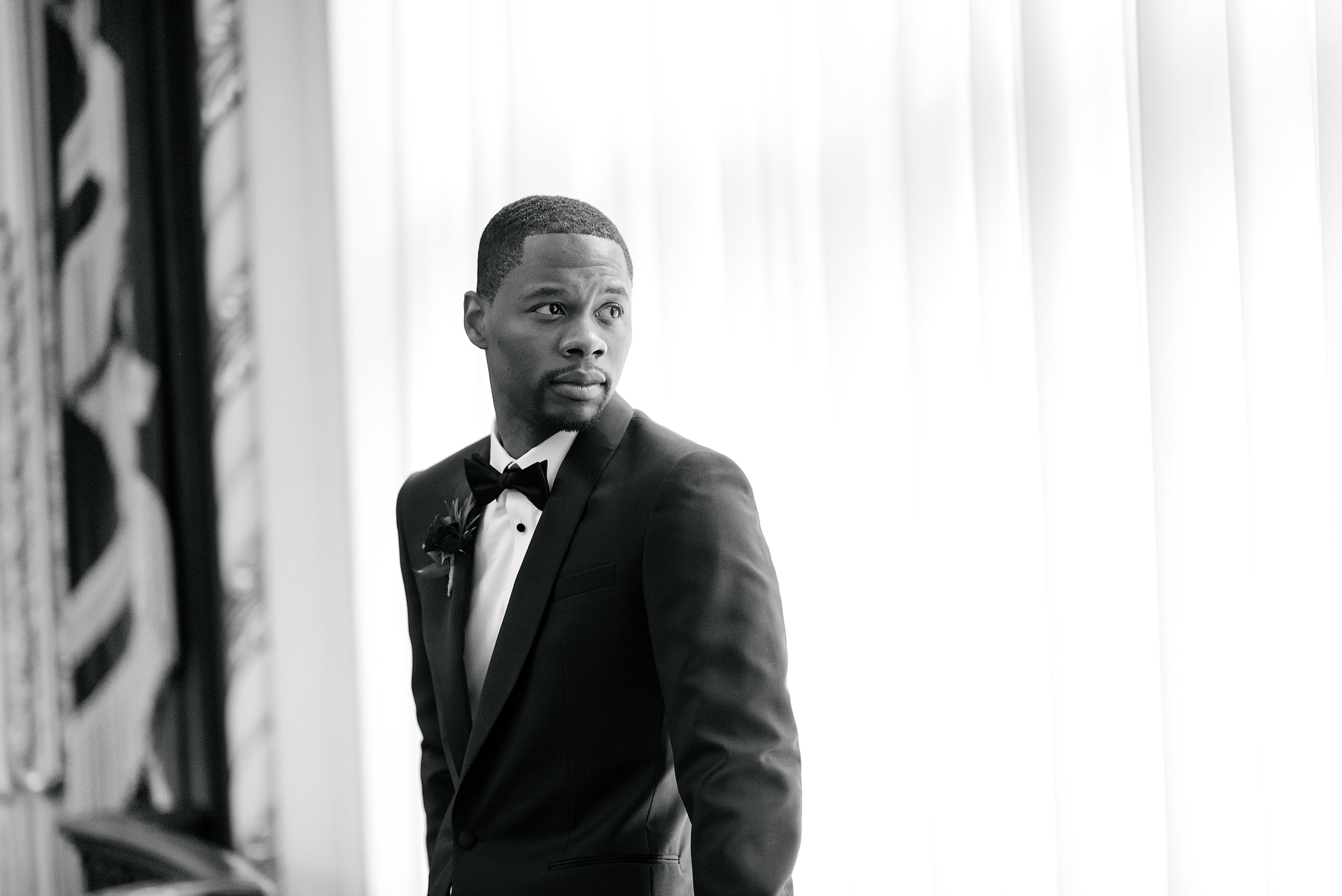 Groom in a tuxedo beside a bright window at Heinz Hall