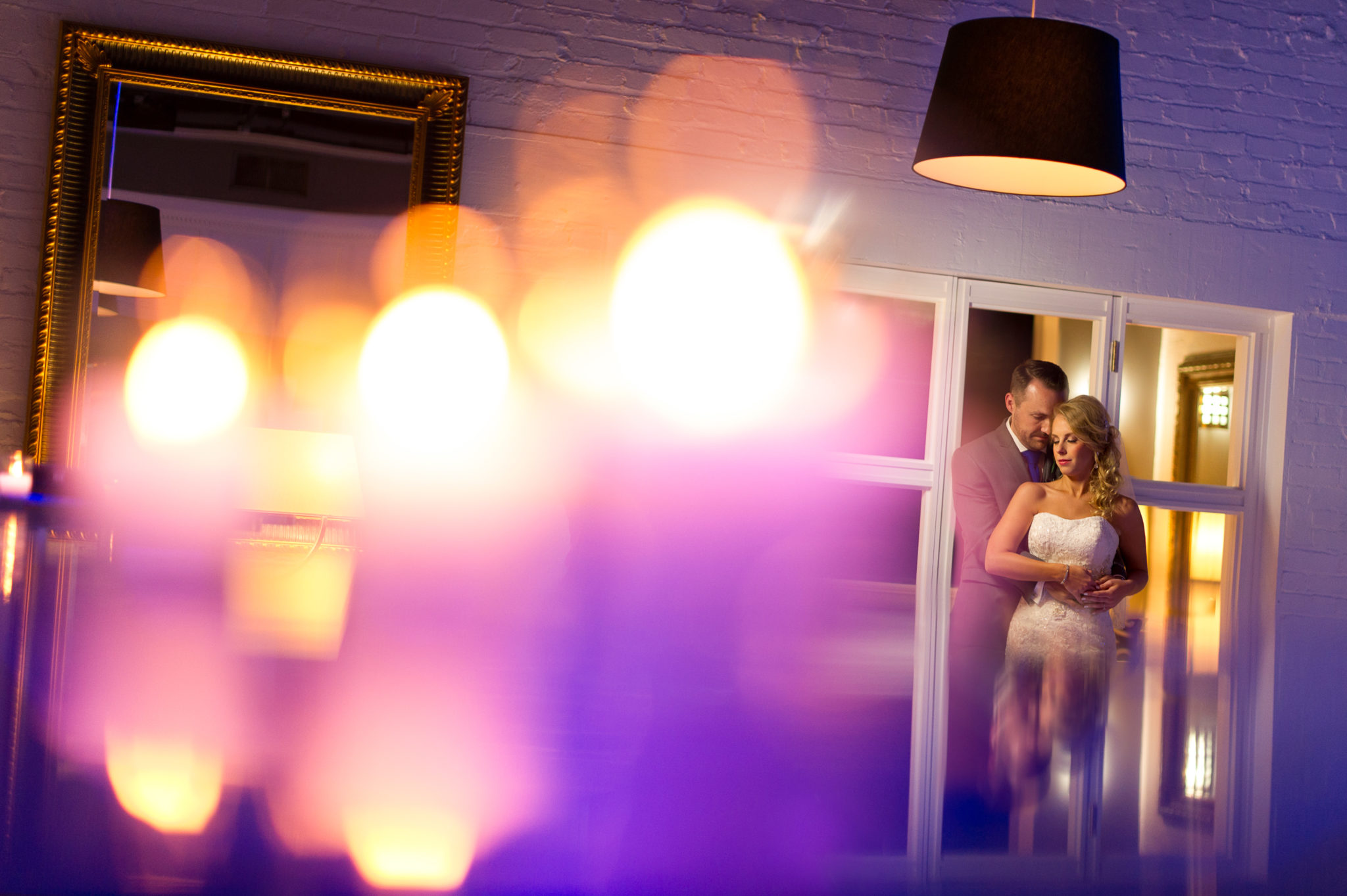 Bride and groom seen through colorful reception lights at J. Verno Studios