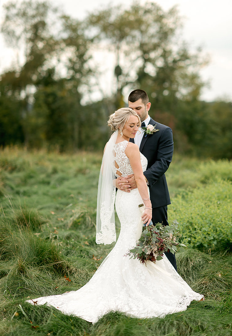 Bride and groom standing together in a meadow at Longue Vue Club