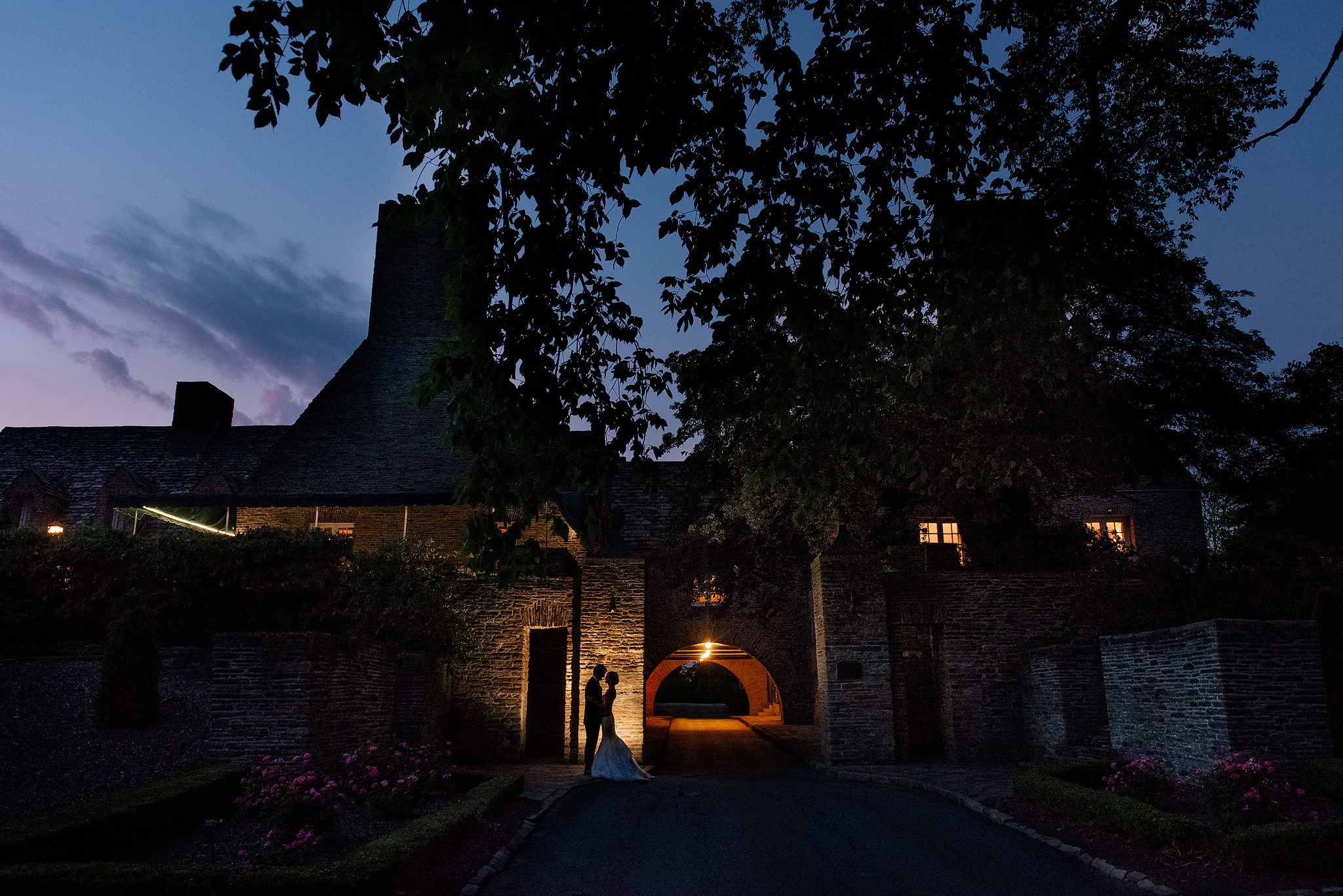 Nighttime exterior of Longue Vue Club with the wedding couple beneath a lit arch
