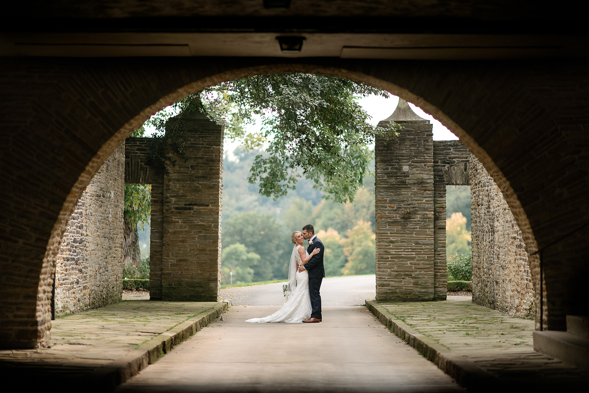 Bride and groom framed by a stone arch at Longue Vue Club